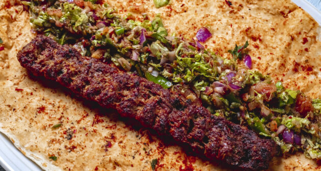 side view lulya kebab with red onion geens hot green pepper salt and pepper on pita